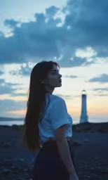a woman with long hair standing in front of a lighthouse