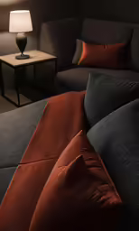 a gray and brown couch sitting in a room with a lamp