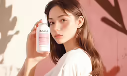 an asian woman holds a pink bottle of kerata skin care