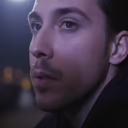 man with dark hair and blue eyes with a spotlight
