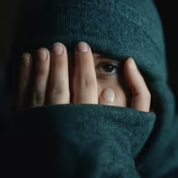 a woman covering her face in a green blanket