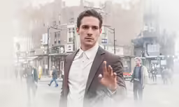 man in a suit and shirt is holding his hands out and looking at the camera