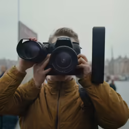 a woman with camera around her neck with the photographer looking through it