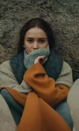 a woman with a blanket on her face sitting outside