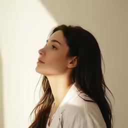 a woman in a white shirt looking off into the distance