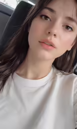 a young woman sitting down looking up with a smirk on her face