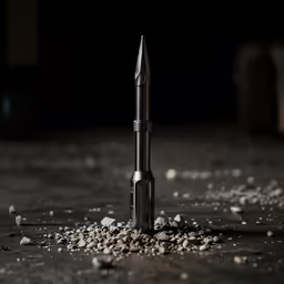 this is a close up photo of an old drill lying on some gravel