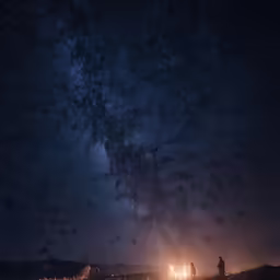 two people on hill top at night with bright lights