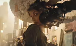 a woman holding a camera looking at a building in the city