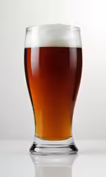 a glass filled with dark liquid on top of a white table