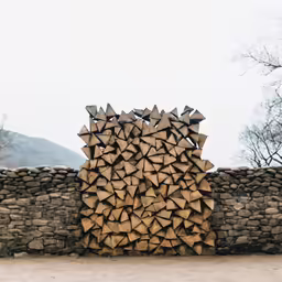 a stack of wood logs sitting on top of a dirt field