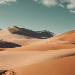 a landscape of sand dunes and mountains with clouds