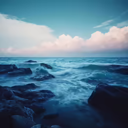 a dark blue sea with a bunch of large rocks in the foreground
