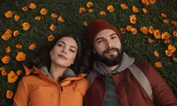 a man and woman are lying on the ground with flowers