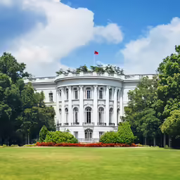 a white building in a park, surrounded by trees