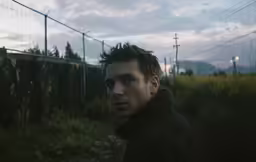 a man standing in front of a fence with barbed wire on it