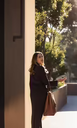 a woman standing against the wall outside in black
