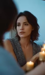 a woman sitting down next to candles