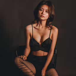asian woman in black sheer clothing sitting in a chair,an asian woman wearing a sheer bralet and stockings sitting on a chair