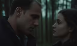 a man and woman standing in the woods