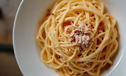 a white bowl filled with spaghetti and sauce