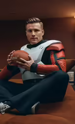 a man in black and red is holding a football
