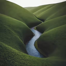 a stream running through a lush green hilly landscape