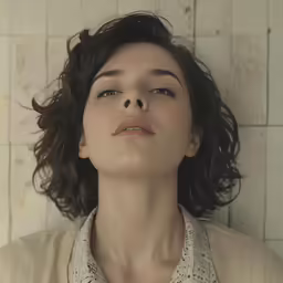 a woman in a shirt standing against a wall