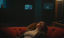 a woman laying on the couch in a dark room