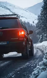 a vehicle with its rear light on going down the road in the snow