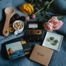 a table topped with a camera, bowl of cereal and flowers