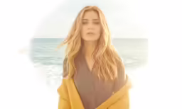 a woman standing at the beach under a blanket