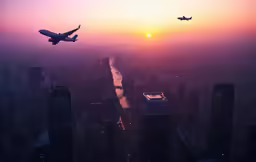 two planes flying over a city and an orange and purple sky