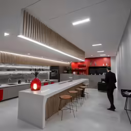 the large kitchen with white marble counter tops has red accents