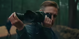 a man taking a picture with his camera in a wooded area