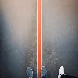 a pair of feet standing on a orange stripe