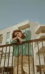 the person leaning against the fence in front of the building