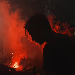 a man standing next to a fire that looks like it is on fire