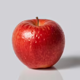 a red apple sitting on top of a white table
