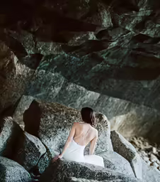 a woman is sitting on a rock in the water