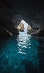 an archway of water leading to a light at night