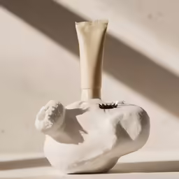 white ceramic vase with a cream bottle inside of it