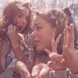 two girls that are standing together with their hands up