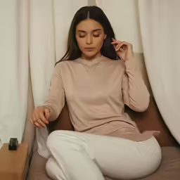 a woman sitting down with one hand in her hair