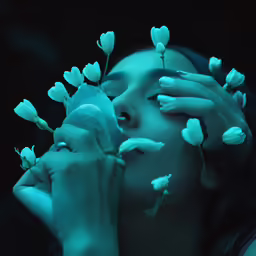 a woman holds some flowers to her face and is covered in green light