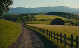 a dirt road next to a lush green hillside