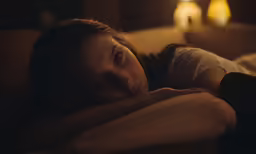 a woman is laying on a couch next to some candles