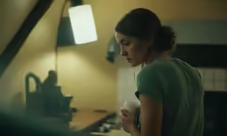 a girl in the kitchen drinking out of her coffee cup