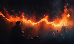 man sitting on table next to large flame
