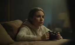a woman laying on a bed holding a camera